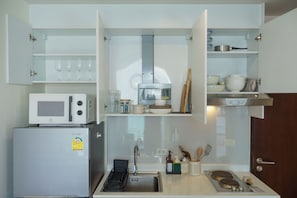 Une cuisine compacte équipée d’un four à micro-ondes, d’un réfrigérateur, d’un évier et d’une hotte aspirante.