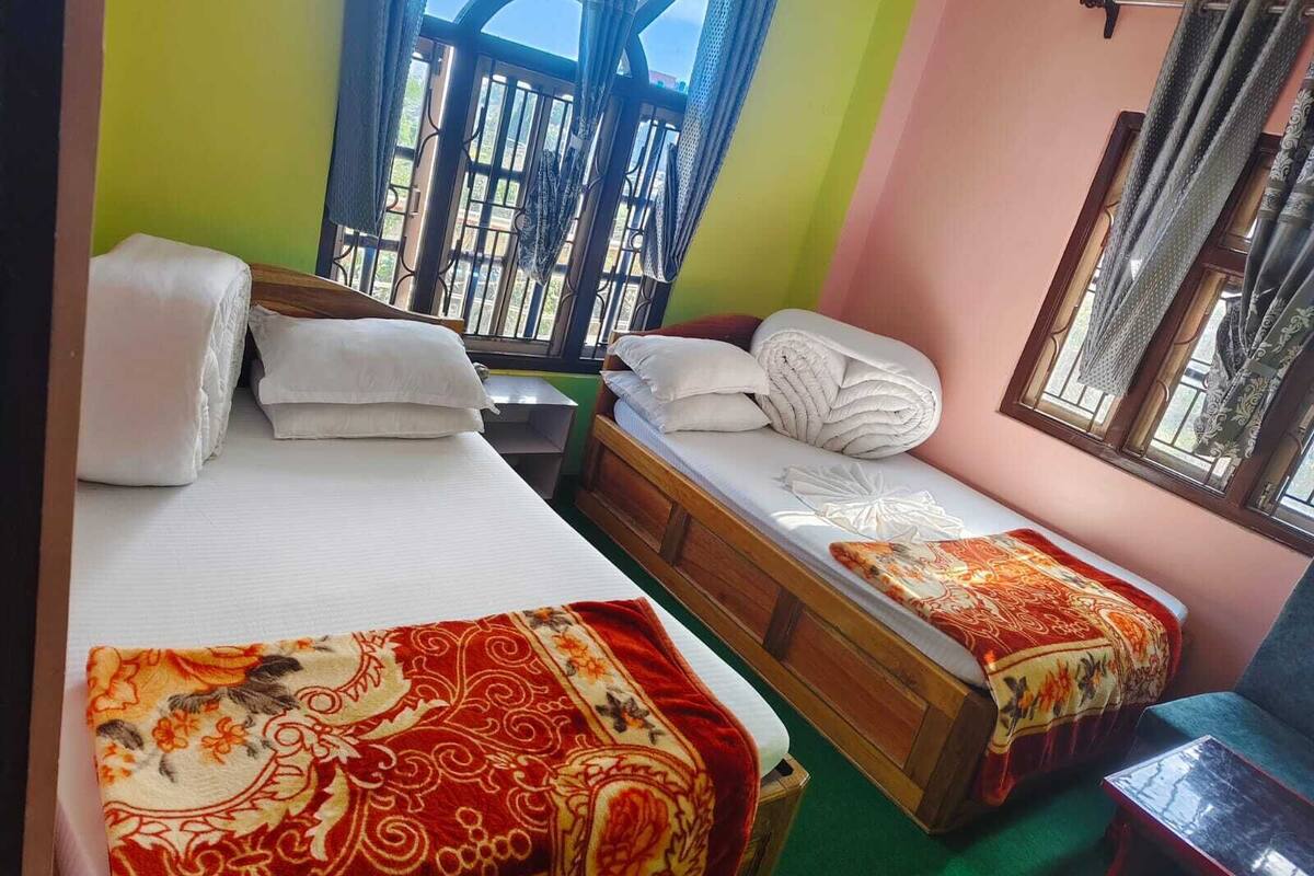 A room with two beds, a small table, and a window with curtains.