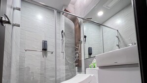 A modern bathroom with a glass shower enclosure, a white toilet, and a sink with a mirror. - HeShan B&B (Hualien City)