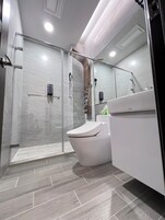 Een moderne badkamer met een douchecabine van glas, een wit toilet en een wastafel met spiegel.