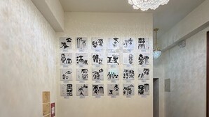 A hallway with a wooden bench, a chandelier, and a wall with calligraphy. - HeShan B&B (Hualien City)
