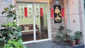 A building entrance with a sign indicating the address, a glass door, and several potted plants. - HeShan B&B (Hualien City)