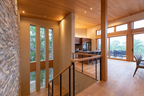 A modern interior with a staircase, wooden ceiling, and large windows.