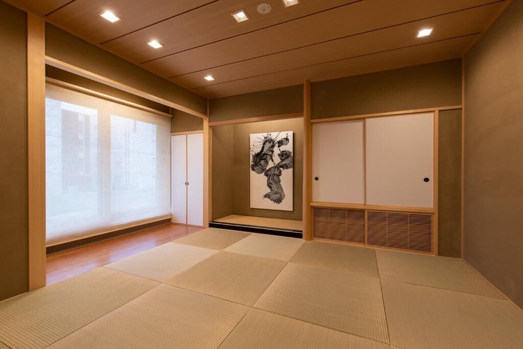 A traditional Japanese room with tatami flooring, sliding doors, and a framed artwork on the wall.