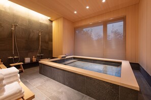 A modern bathroom with a large bathtub, shower, and wooden accents.