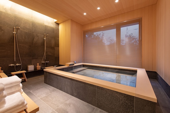 A modern bathroom with a large bathtub, shower, and wooden accents.