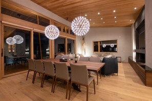 A modern dining area with a wooden table, chairs, and pendant lights.