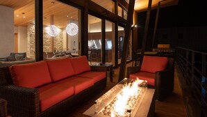 Ein modernes Interieur mit Holzbalkendecke, großen Fenstern, einem roten Sofa und einem Kamin.