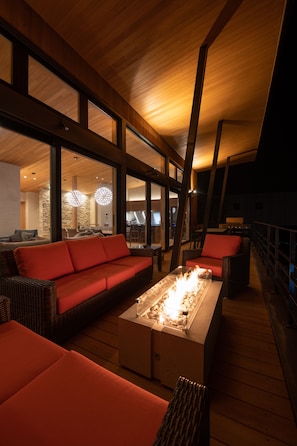A modern interior with a wooden ceiling, large windows, a red sofa, and a fireplace.