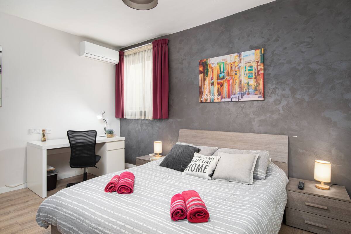 Une chambre d’hôtel moderne équipée d’un lit, d’un bureau et d’une table de chevet.