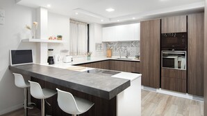 Een moderne keuken met een centraal eiland, barkrukken, een inbouwoven en een magnetron.