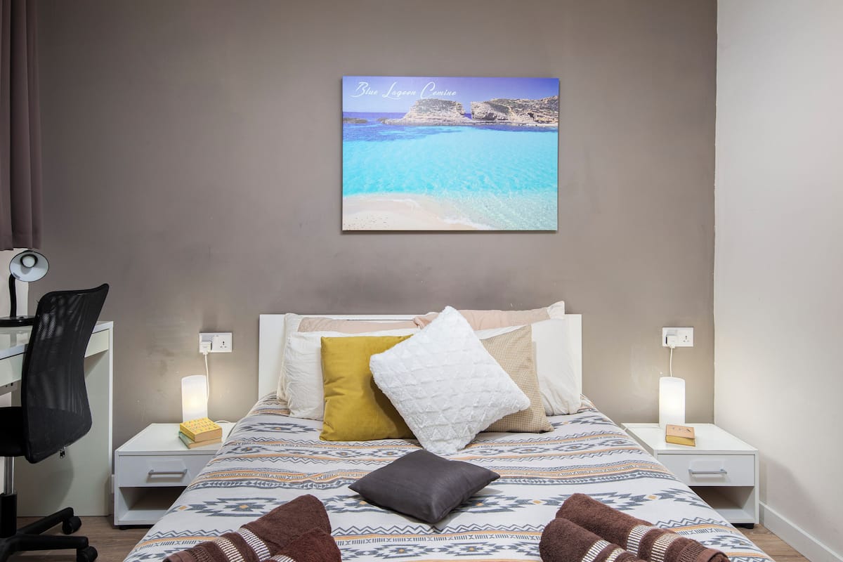 Une chambre à coucher comprenant un lit, des tables de chevet, un bureau et une chaise.
