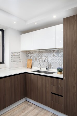 Una cocina moderna con armarios blancos, encimera de madera, pileta y un salpicadero con diseño.