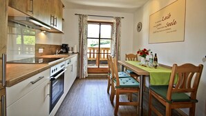 Una cocina con armarios de madera, una mesa de comedor con sillas y vistas por una ventana.