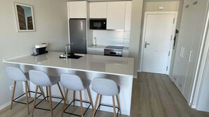 Una cucina moderna con un'isola centrale, sgabelli da bar, frigorifero, microonde e piano cottura.
