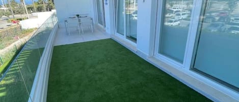 Un balcón con césped artificial, una zona de estar y vistas a un estacionamiento.