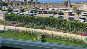 Un parcheggio con diverse auto, palme e un edificio sullo sfondo.