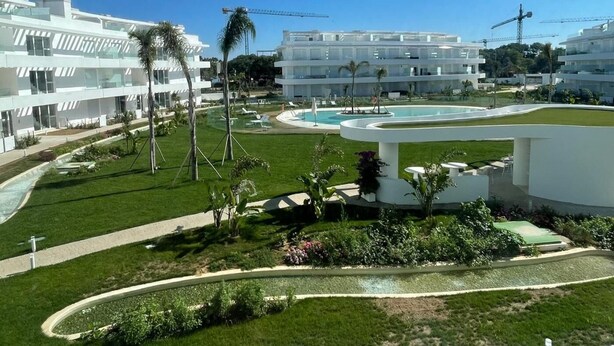 Un hotel moderno con piscina, palme e cielo azzurro.
