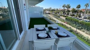 Un balcone con un tavolo apparecchiato per due persone, con vista su un'area parcheggio e del verde.
