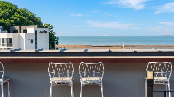 A seaside terrace with white chairs, a view of the ocean, and a building labeled 'MARIPLA'.