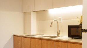 A modern kitchen with a stainless steel sink, wooden cabinets, and a built-in microwave.