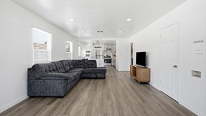 Ein modernes Wohnzimmer mit einem Ecksofa, einem Fernseher und einem Holzschrank.