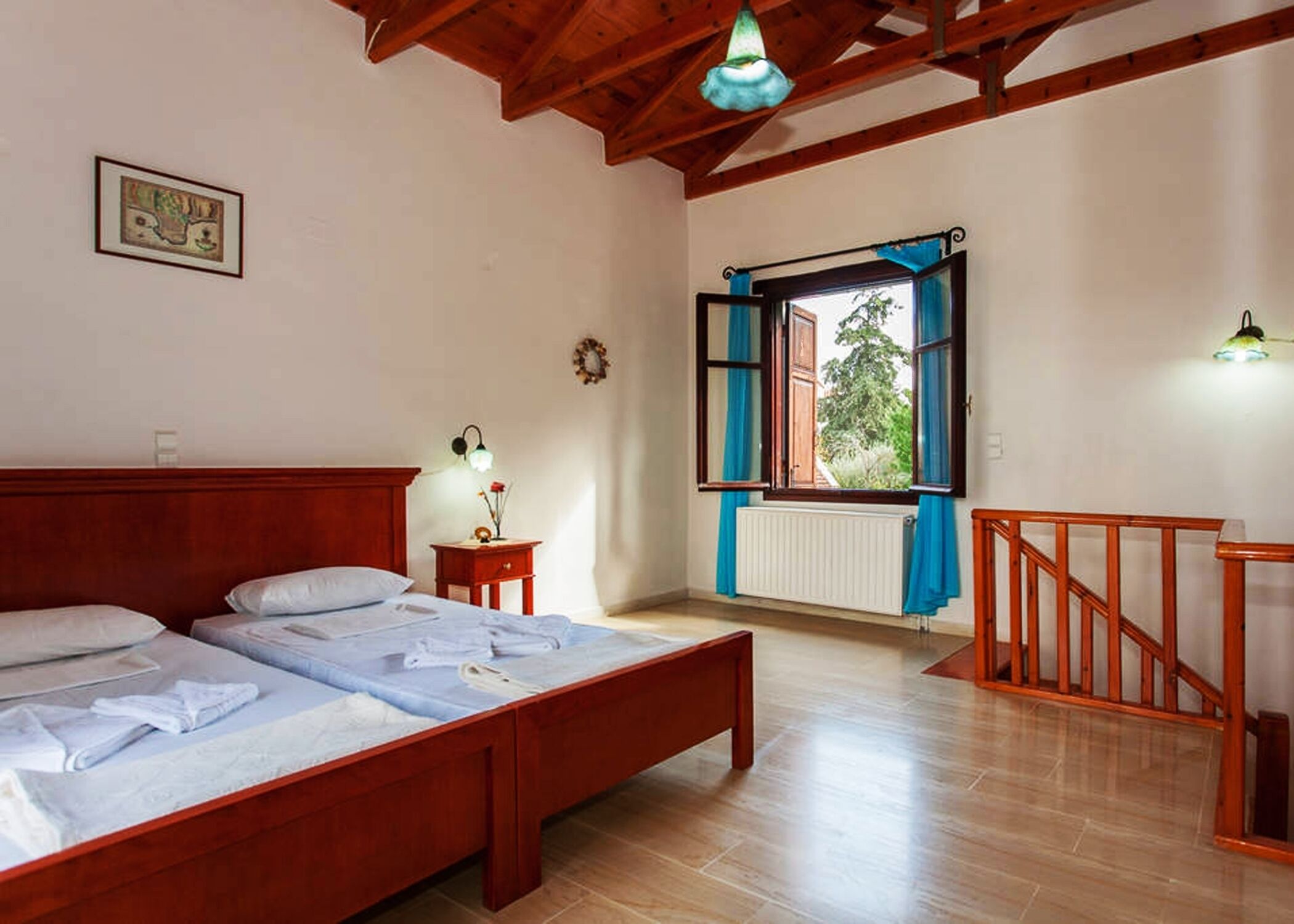 Un dormitorio con una cama de madera, una mesita de noche, un ventanal con cortinas azules y una escalera de madera.