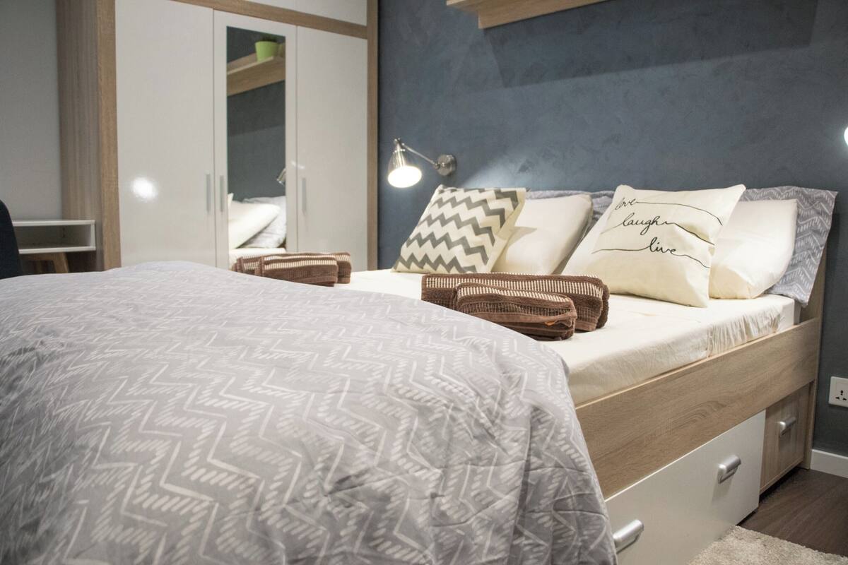 Une chambre à coucher avec un lit, une lampe de chevet, des oreillers et une armoire.