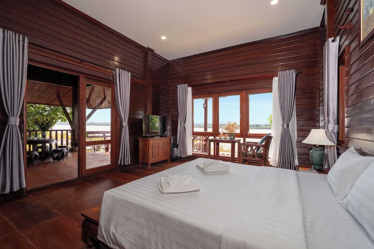 A wooden-paneled room with a bed, a TV, and a view of the outdoors.