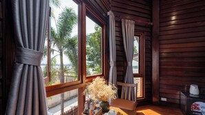 A wooden room with a table, a vase of flowers, and a view of palm trees outside.