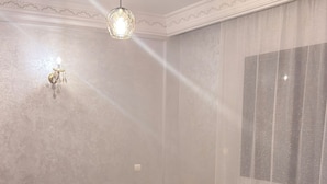 Una sala menjador amb taula rodona, sis cadires, un penjallum i estores amb dibuixos.