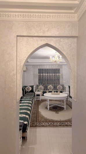 A room with a sofa, a round coffee table, and a patterned rug. - Gorgeous 3-bedroom apartment with AC in vibrant Marrakech downtown (Marrakech)