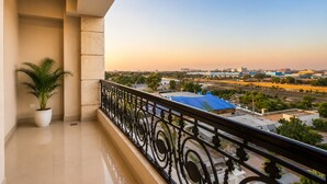 A balcony with a potted plant, a view of a cityscape, and a clear sky. - The Amberly Gardens (Sanwer)