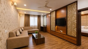 A modern living room with a sofa, coffee table, TV, and decorative paneling. - The Amberly Gardens (Sanwer)