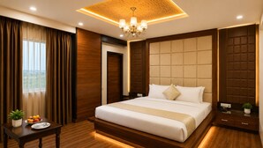 A modern hotel room with a large bed, wooden flooring, a ceiling light, and a view of the outdoors. - The Amberly Gardens (Sanwer)