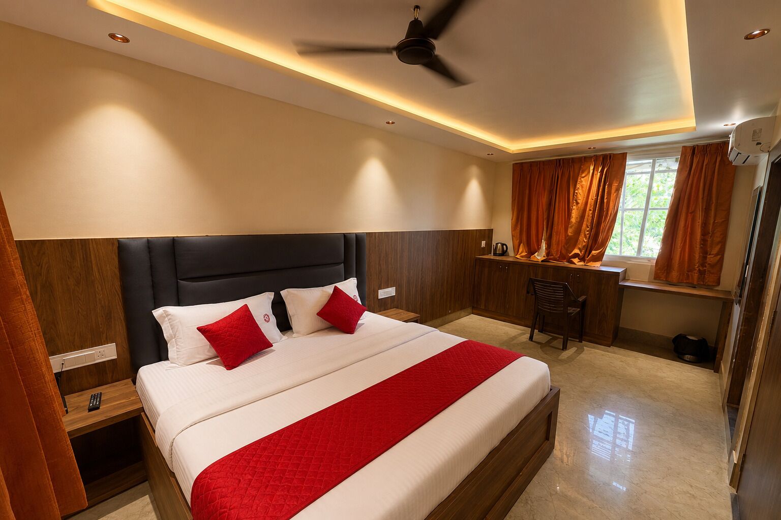 Een hotelkamer met een bed, een bureau, een stoel en een plafondventilator.