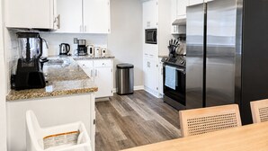 Eine moderne Küche mit weißen Schränken, einem Edelstahl-Kühlschrank, einer Kaffeemaschine und einem Mixer.