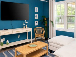 A room with a TV, a desk, a wicker chair, a bed, and a window with curtains. - 4BR Coastal Look, Pool House, Pets welcome (Columbus)