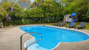 Ein Schwimmbad mit Rutsche, Liegestühlen und einer Spielanlage.