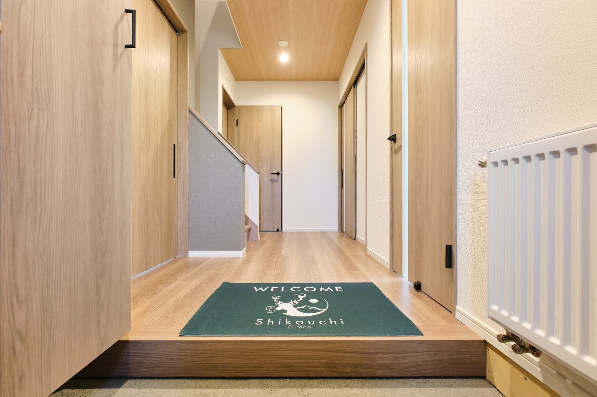Un pasillo con paredes de madera, una alfombra de bienvenida y un radiador.