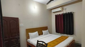 Un dormitorio con una cama, una silla de madera, un escritorio, un ventilador de techo y un armario.