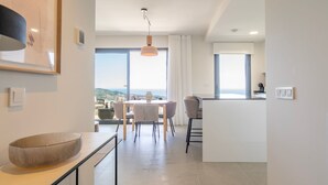 Een moderne keuken met een groot eiland, een eetgedeelte met uitzicht en een ruime woonkamer met een groot raam.