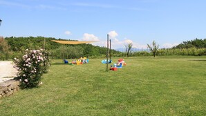 Un campo cubierto de césped con un parque infantil y un muro de piedra.