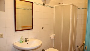 Un baño con lavamanos, inodoro y cabina de ducha.