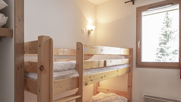 A bunk bed room with a window, wooden flooring, and a wall-mounted heater. - Apartment in Valfrejus Near Gondola (Modane)