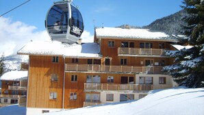 A wooden building with multiple balconies, a ski lift, and snow-covered surroundings. - Apartment in Valfrejus Near Gondola (Modane)