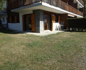 Ein modernes, zweistöckiges Haus mit Natursteinfassade, großen Glasüren und einem Holzbalkon.
