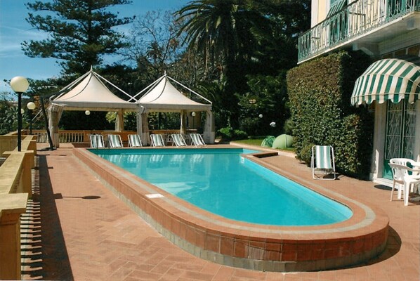 A swimming pool with lounge chairs, a gazebo, and a covered seating area. - Wohnung in Residenz Porto (Imperia)