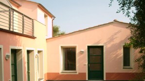 A two-story building with a flat roof, a small front yard with stepping stones, and a green door. - Ferienwohnung fur 4 Personen in Imperia (Imperia)