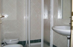 Casa de banho com sanita, cabine de duche e lavatório.